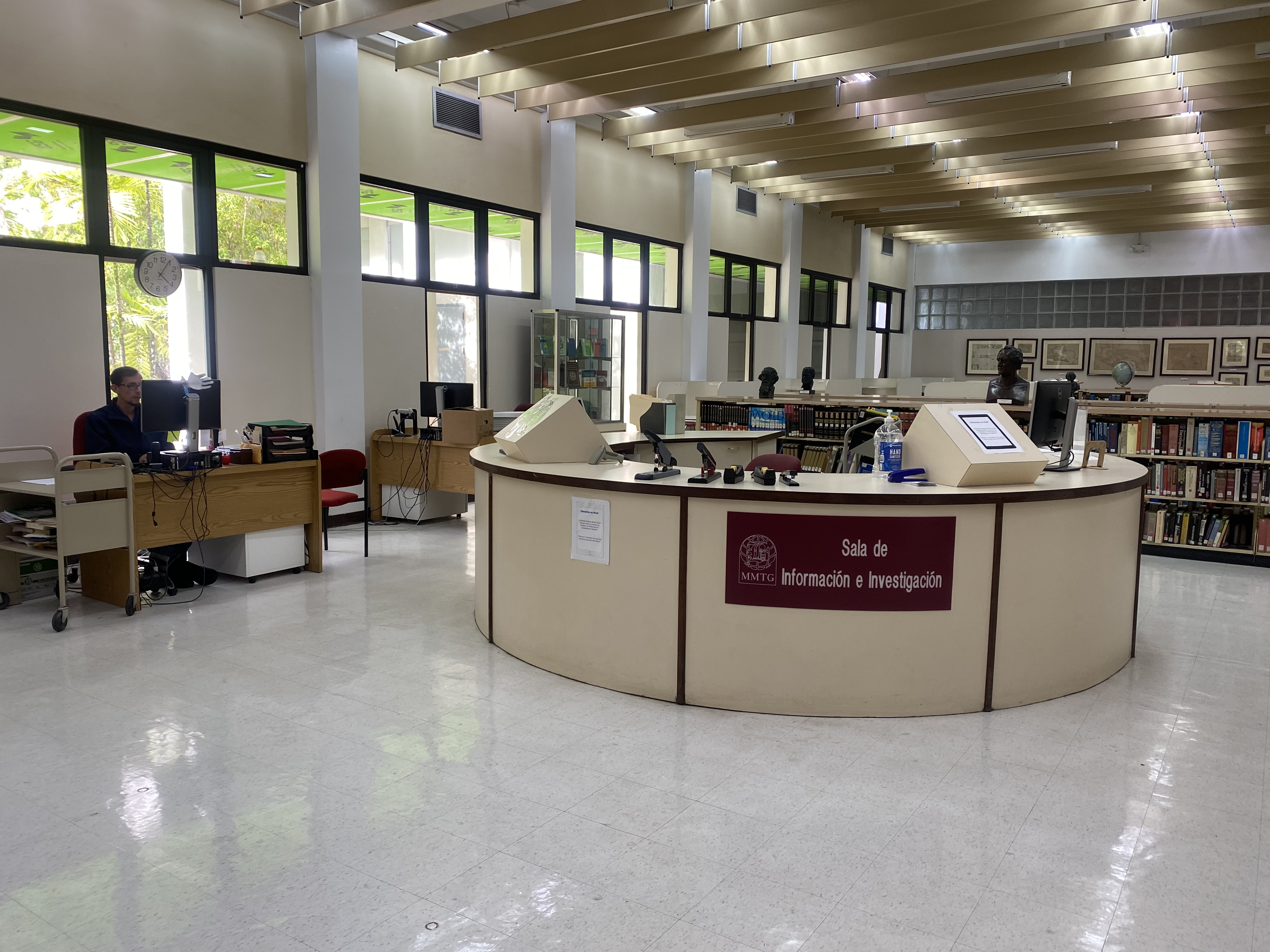 Imagen Espacio fisico de la sala de informacion e investigacion de la biblioteca. Mostrador en forma circular con anaqueles de libros en la parte posterior.