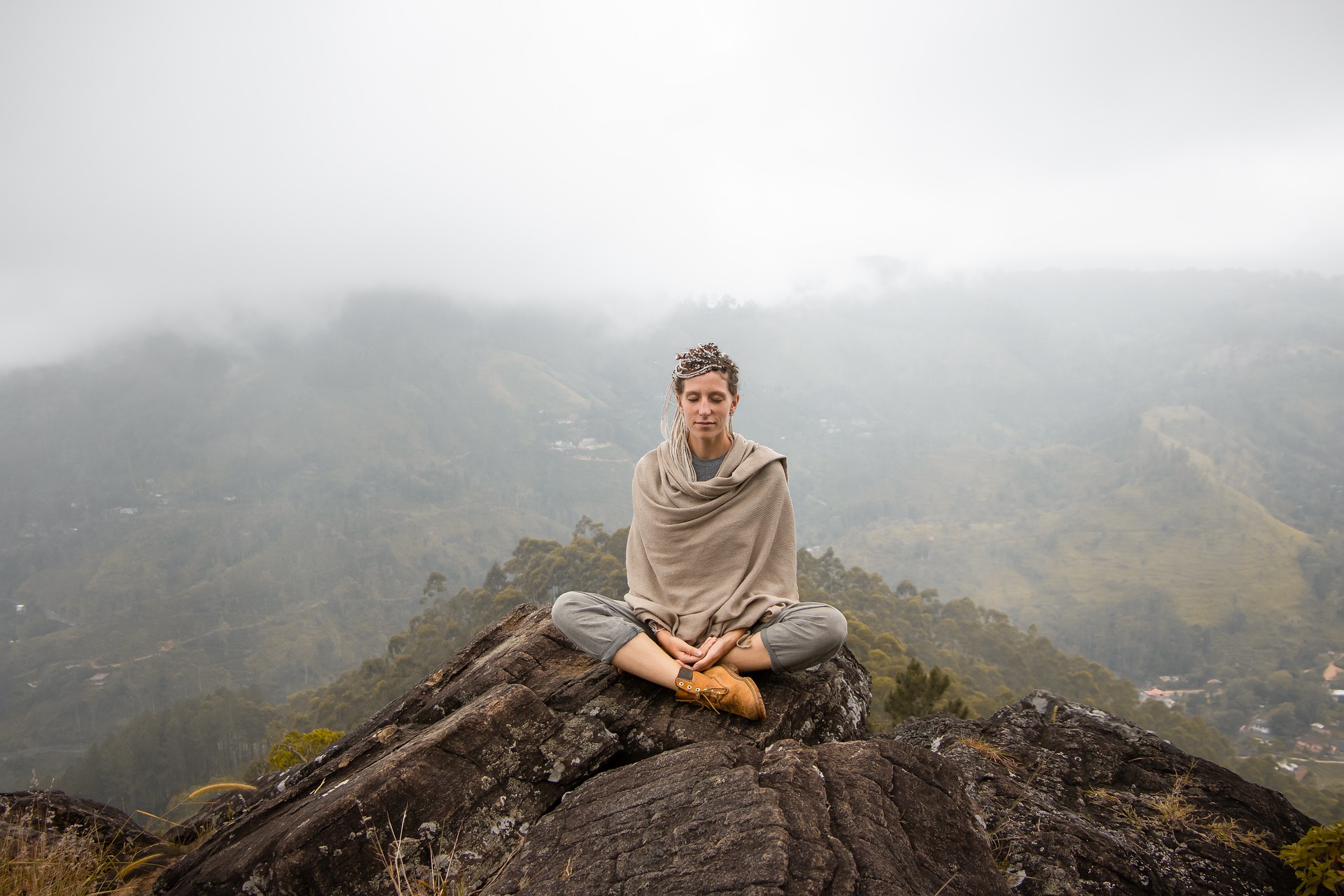 imagen mujer meditando en postura flor de loto sobre una montaña